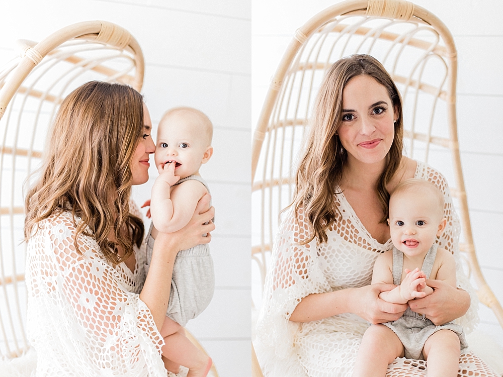 Brunette mom with loose curls in cream Zara dress sitting in rattan chair from world market holding blonde baby boy in grey Zara overalls in natural light studio with Tampa newborn photographer Marisa stone photography