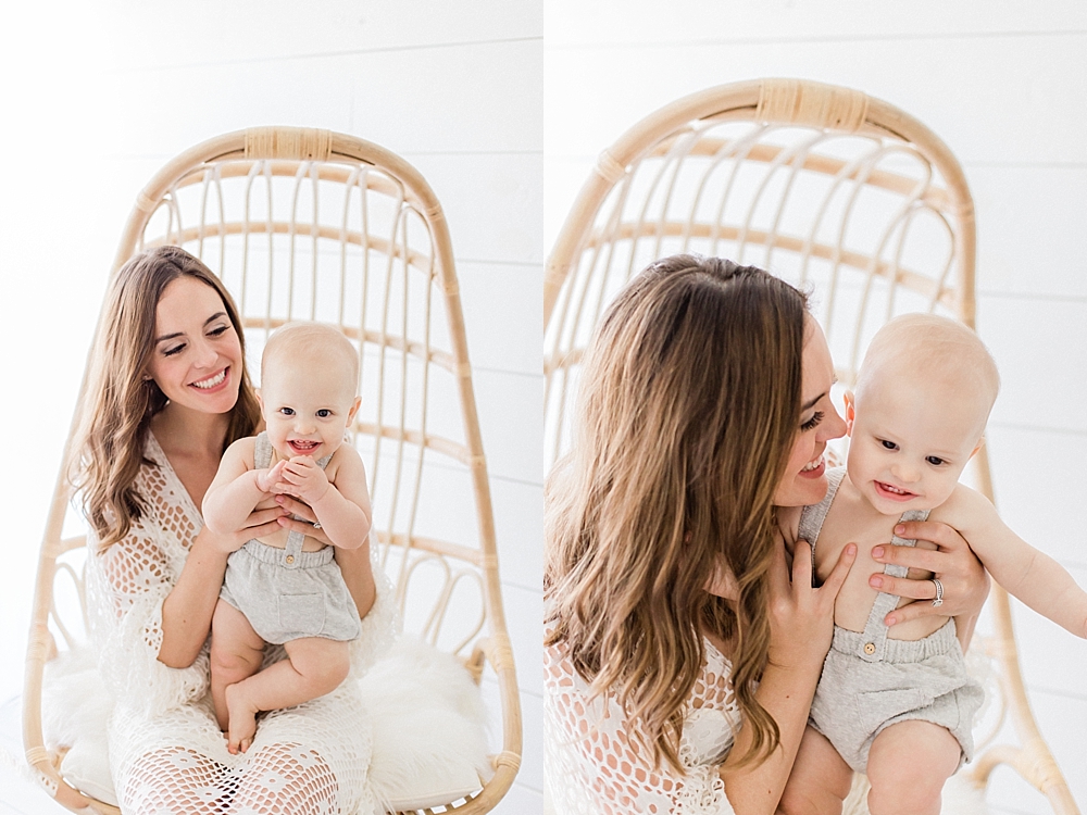 beautiful mom in white Zara maxi dress sitting in rattan world market chair with baby boy in grey zara jumper on her lap smiling in natural light studio by Tampa family photographer Marisa stone photography